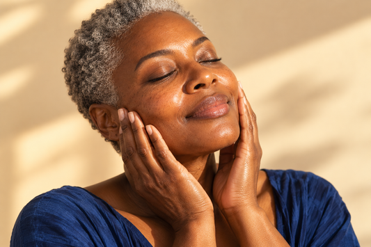 Femme à la peau noire posant délicatement ses mains sur ses joues, geste doux envers sa peau